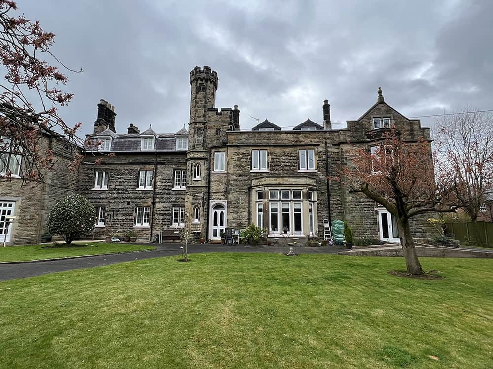 Historic castle-like building with turrets and a well-maintained lawn.