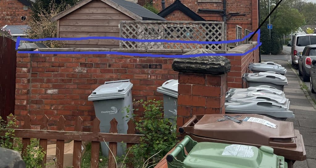 Clothesline with blue rope above a brick wall in a residential area.