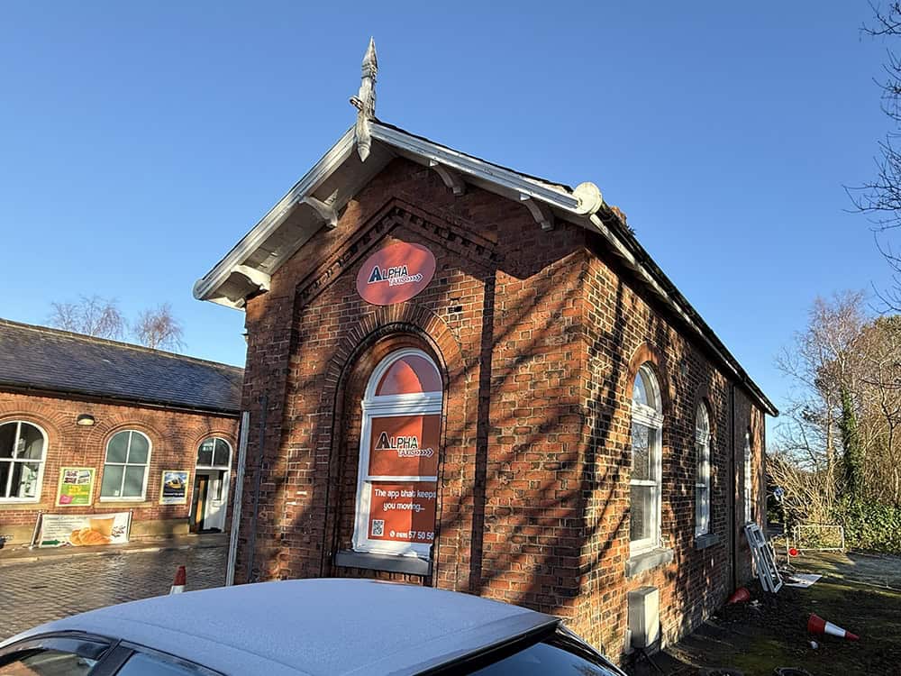 Historic brick building with restoration work and clear blue sky.