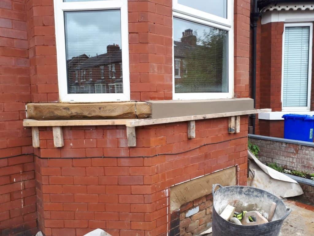 Brick window sill repair with new concrete and wooden support.